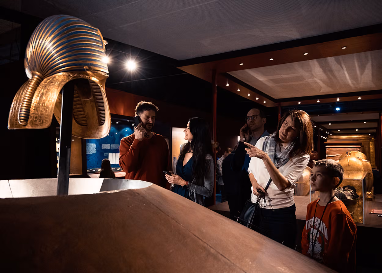 Besucher betrachten eine goldene Maske und Sarkophag 2023 in einem Museumsausstellung über das alte Ägypten.