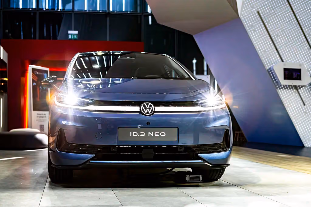 Der VW ID.3 NEO steht mit eingeschaltetem Licht auf einer Messe, aufgenommen 2023.
