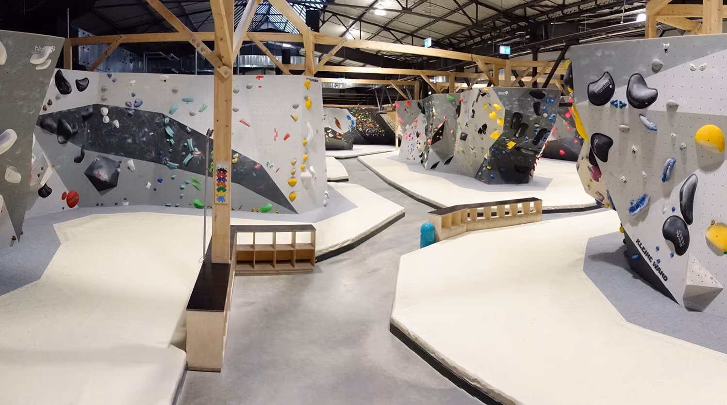 Leere Boulderhalle mit farbigen Griffen und Polstern, aufgenommen an einem ruhigen Tag.