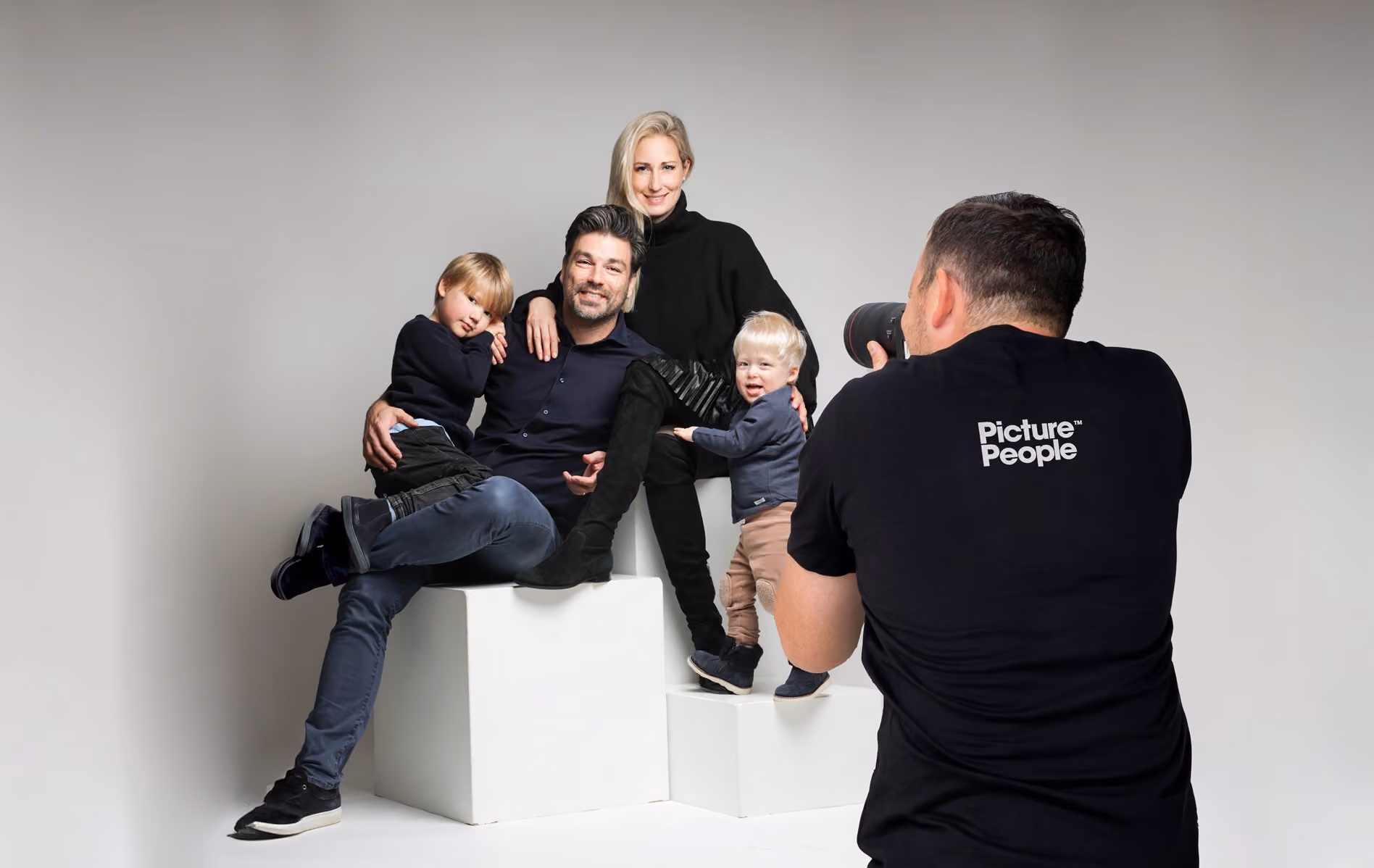 Im Studio macht ein Fotograf 2024 ein Porträt von einer Elternpaar mit zwei kleinen Kindern.