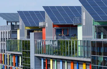 Blick auf ein Wohnquartier mit modernen Reihenhäusern mit Solarmodulen auf den Dächern.