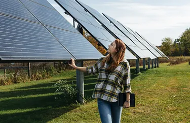 Agri- und Floating-PV-Anlagen leisten einen Beitrag zur erneuerbaren Energieerzeugung. Eine Frau begutachtet die Solarmodule einer Agri-PV-Anlage.