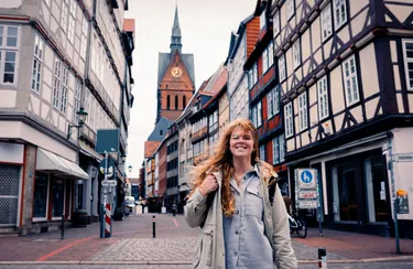 Eine junge Frau spaziert durch die Altstadt von Hannover, im Hintergrund sind Fachwerkhäuser zu sehen.