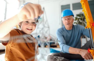 Ein Junge baut ein Modell eines Strommastes zusammen mit seinem Großvater zu Hause auf.