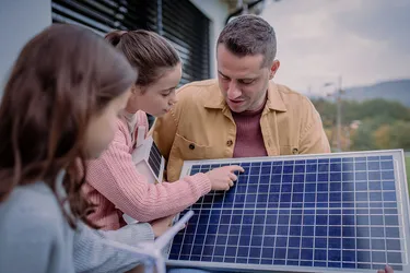 Ein Vater erklärt seinen beiden Kindern, wie ein Solarpanel aufgebaut ist. 