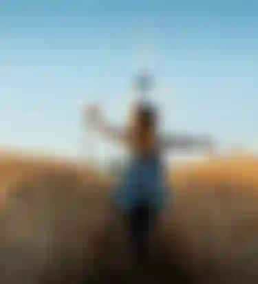 Mädchen läuft durch ein Feld mit Windenergieanlagen