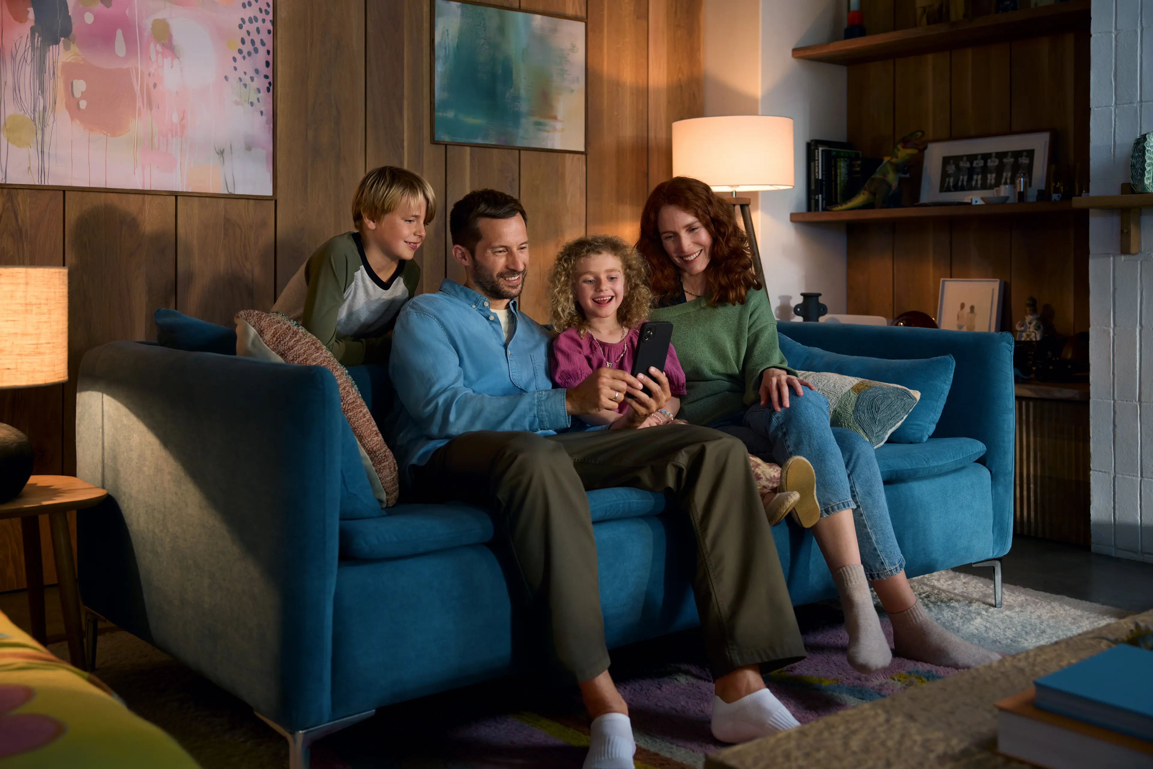 KV03_Family_Living_Room_0457_sRGB Familie sitzt auf Sofa und schaut auf das Handy