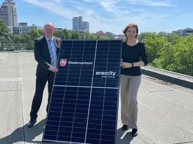 Finanzminister Reinhold Hilbers und enercity-CEO Dr. Susanna Zapreva stehen auf dem Dach und halten ein PV-Anlage