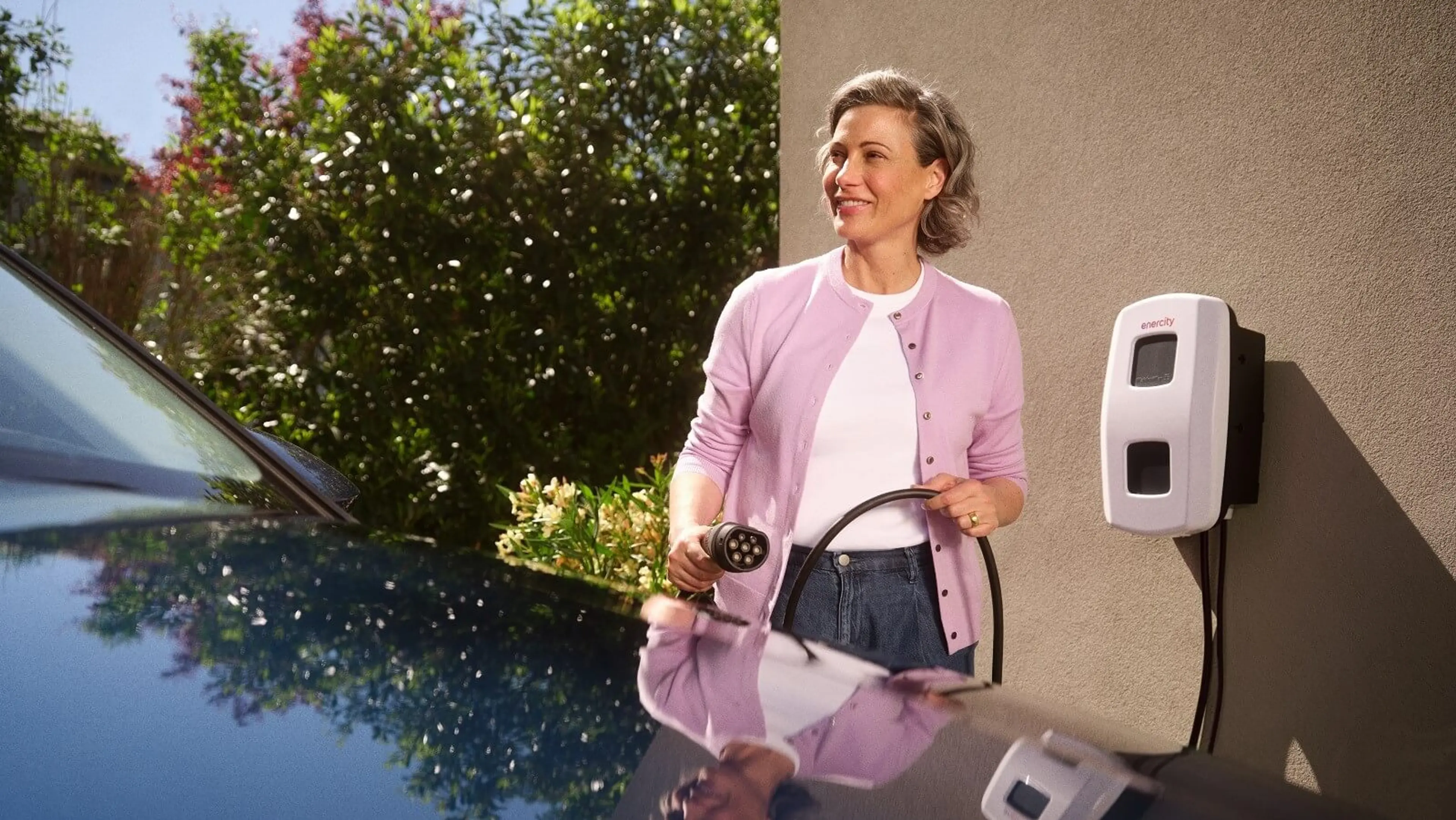 enercity SmartLaden Frau steht vor einer Wallbox und hält ein Ladekabel in der Hand