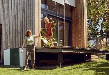 Mutter und Tochter vor Haus mit Wärmepumpe