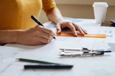 Eine Frau arbeitet mit einem Stift an einem Bauplan.