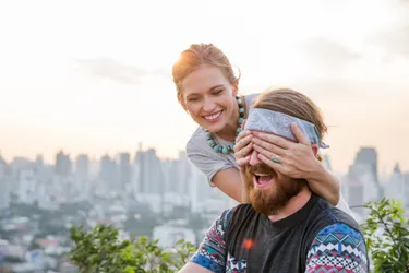 276bd687-7af0-44bb-8d32-1185ef4a0fae-woman-holds-hands-over-mans-eyes-surprise