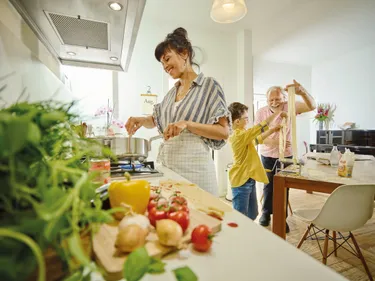 Eine Familie bereitet gemeinsam Essen in einer modernen Küche vor, umgeben von frischen Zutaten und Kochutensilien.