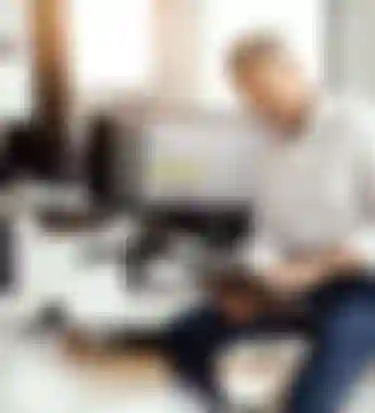 Ein Mann sitzt auf einem Schreibtisch und schaut auf sein Tablet