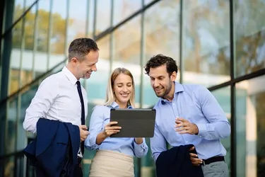 3 Personen schauen auf ein Tablet