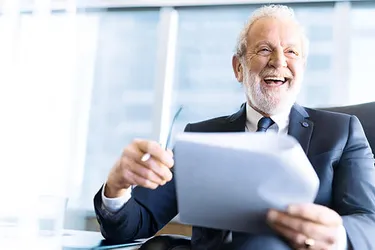 Mann hält Dokumente in der Hand und lacht