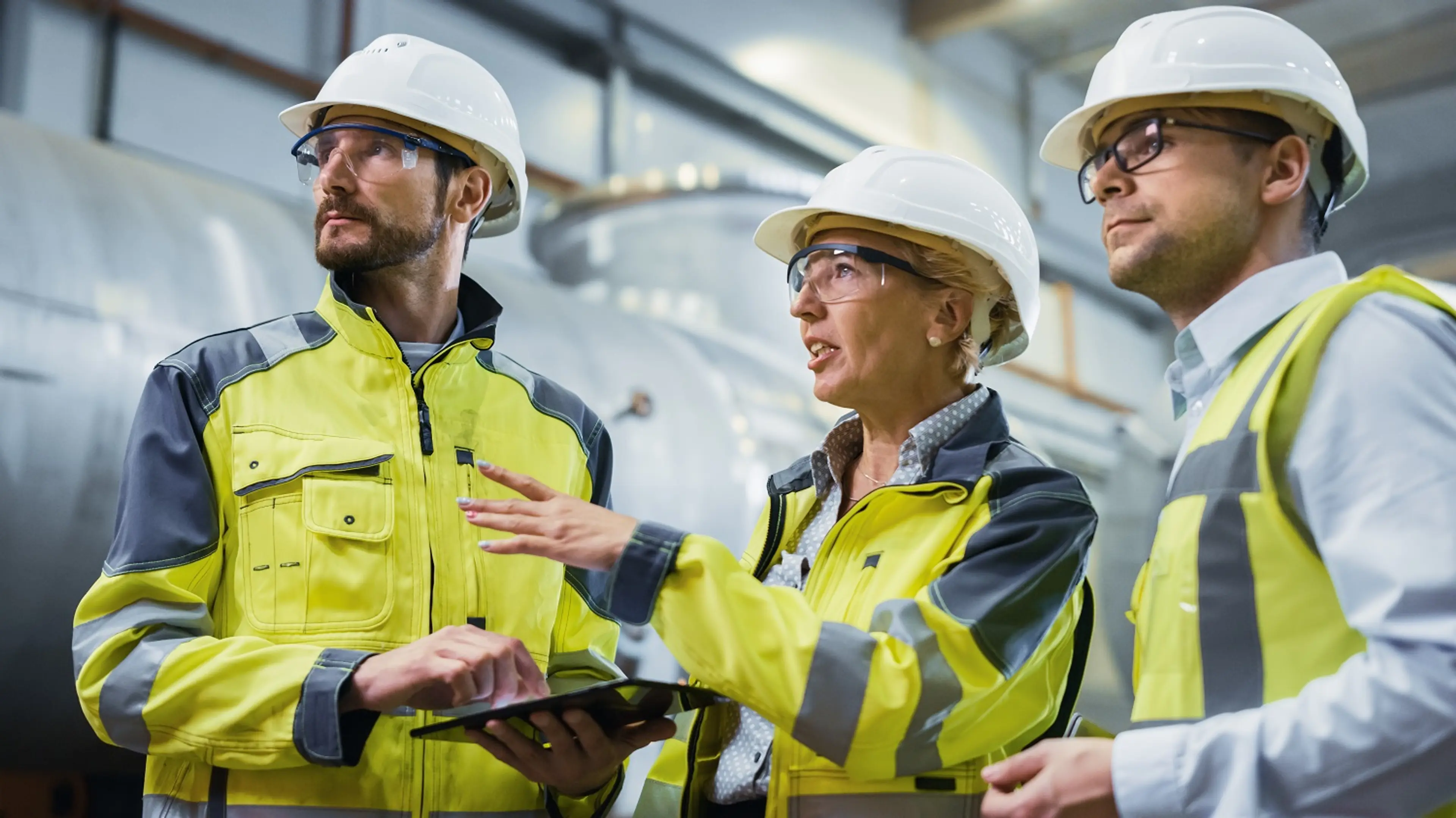 Drei Ingenieure mit Schutzhelm bei der Besichtigung von Anlagen