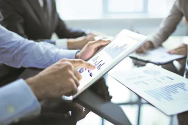 Hände die auf Graphiken auf dem IPad zeigen.