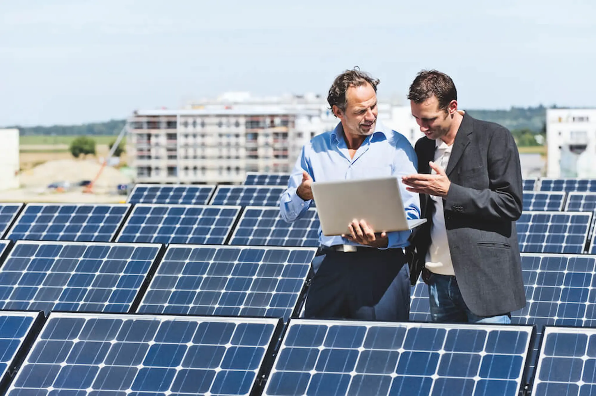 Solarstrom für Businesskunden Zwei Männer stehen vor Solarpanelen und diskutieren über erneuerbare Energien.
