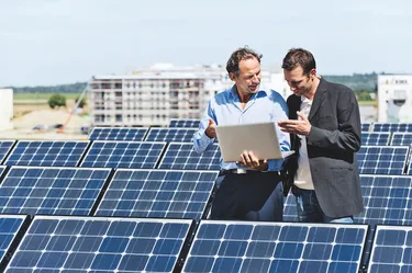 Zwei Männer stehen vor Solarpanelen und diskutieren über erneuerbare Energien.