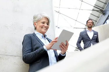 Frau steht auf einer Treppe und schaut auf ihr Tablet