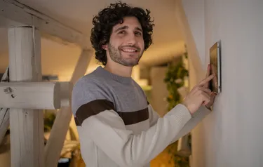 Ein Mann regelt die Temperatur an einem digitalen Heizkörperthermostat