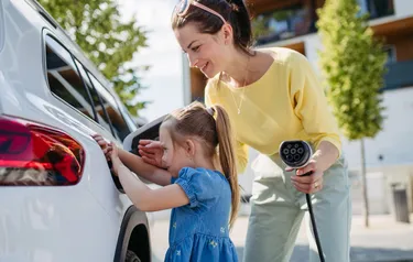 Eine Frau und ein Mädchen beim Laden eines E-Autos