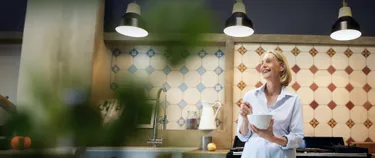 Eine Frau steht entspannt mit einer Schüssel in der Küche.