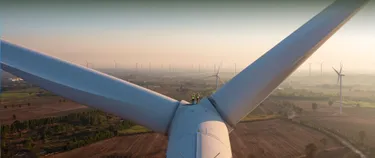 Zwei Menschen stehen zwischen den Rotorblättern einer Windkraftanlage