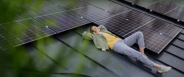 Eine Frau liegt neben PV-Modulen auf dem Dach