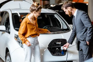Eine Frau beobachtet einen Mann beim Laden eines Elektroautos