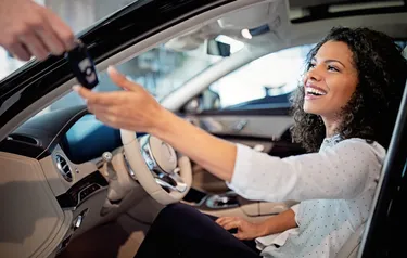 Eine Frau bekommt den Schlüssel für ein gebrauchtes Elektroauto gereicht