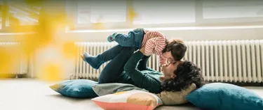 Mutter und Kind im Wohnzimmer vor der Heizung