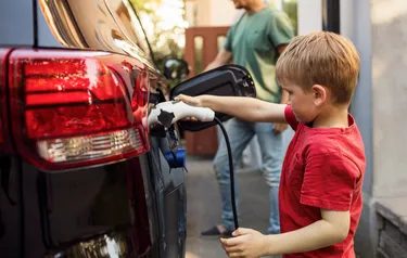 Nahaufnahme eines kleinen Jungen der ein Elektroauto lädt