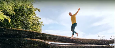 Ein Mann, der auf einem Baumstamm balanciert