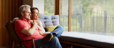 Ein Ehepaar sitzt vor dem Fenster und schaut nach draußen.