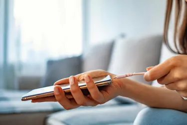 Nahaufnahme einer Frauenhand die ein Ladekabel an ein Handy steckt