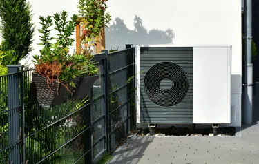 Nahaufnahme einer vor einer Hauswand stehenden Wärmepumpe