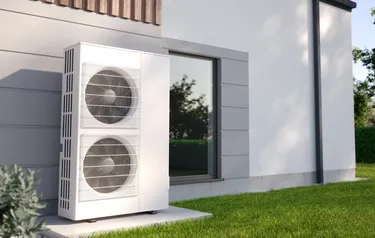 Nahaufnahme einer vor einer Hauswand stehenden Wärmepumpe