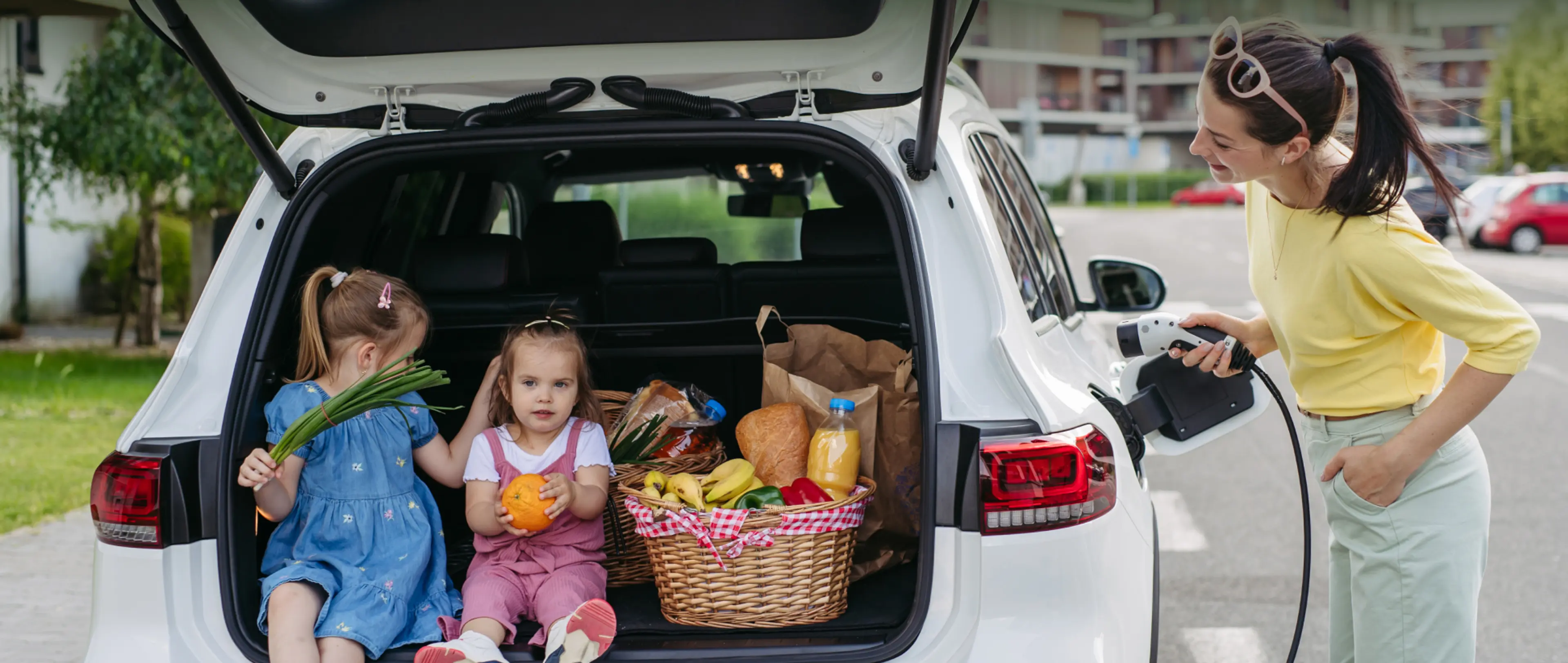 Header_Wallbox-Recht fuer Mieter_innen_GettyImages-1591481473 Frau lädt ein E-Auto mit geöffnetem Kofferraum