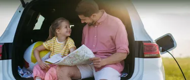 Vater und Tochter sitzen im E-Auto