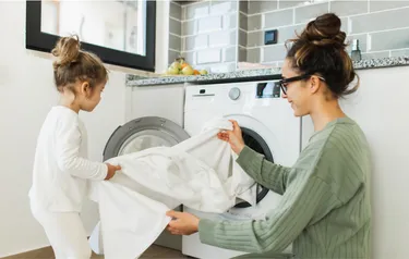 Eine Frau und ein Kind befüllen eine Waschmaschine