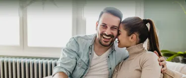 Ein junges Paar sitzt vor einer Heizung.