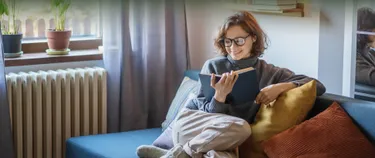 Eine Frau sitzt auf dem Sofa und liest ein Buch.