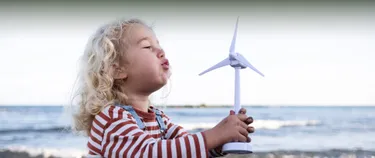 Ein Kind pustet in ein Spielzeug-Windrad