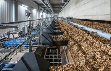 In einem Biomasseheizkraftwerk werden Holzreste auf einem Fließband der Verbrennung zugeführt