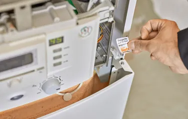 Nahaufnahme eines Gasgeräts auf das ein Techniker einen Aufkleber klebt