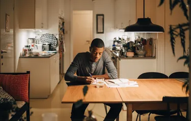 Ein Mann sitzt am Tisch und berechnet seine Energiekosten