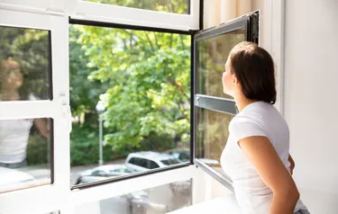 Frau an geöffnetem Fenster 