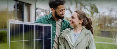 Ein paar mit einem Solarmodul vor dem Haus
